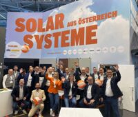 Das Team von Sonnenkraft winkend an einem Messestand.