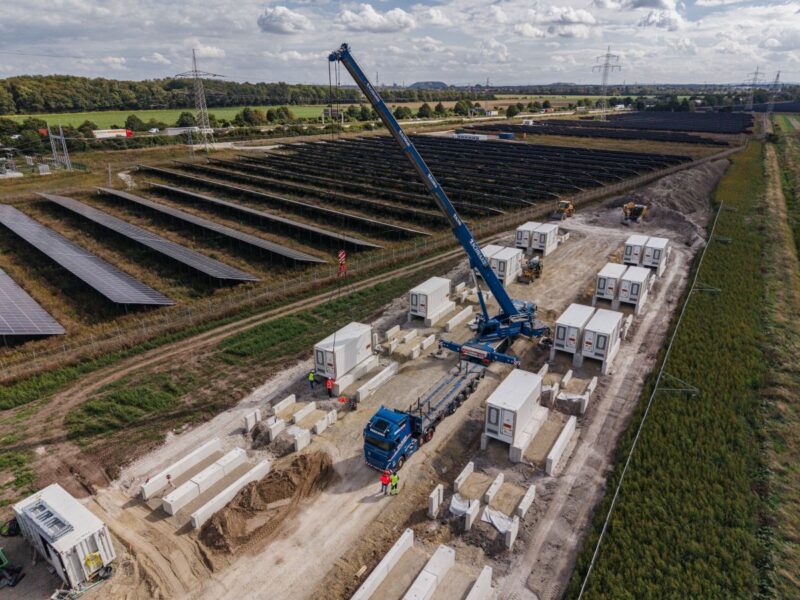 Batteriepark im Bau neben PV-Anlage, die an einer Autobahn liegt.