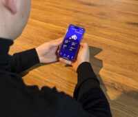 Nuter hält ein Smartphone, das eine App für das Energiemanagement im Haus zeigt.