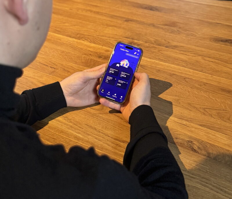 Nuter hält ein Smartphone, das eine App für das Energiemanagement im Haus zeigt.