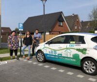 Die Mieterin Silke Schladetzky steht mit der hauseigentümerin udn dem Projektleiter der Husumer Stadtwerke an der Ladesäule für Elektroautos.