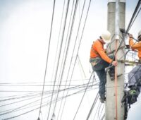 Zwei Männer auf einen Strommast als Symbol für den Stromnetzengpass in Oranienburg.