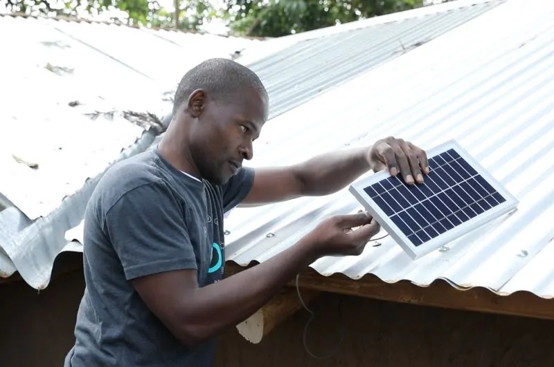 Zu sehen ist ein Mann in Afrika bei der Installation eines kleinen PV-Moduls. „Startup Energy“ ist für Projektideen in Deutschland und Ostafrika gedacht.