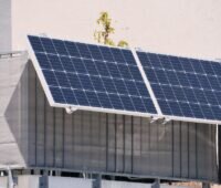 Steckersolargerät an einem Balkon montiert, Solarmodul am Geländer befestigt und über Kabel mit der Wohnung verbunden.