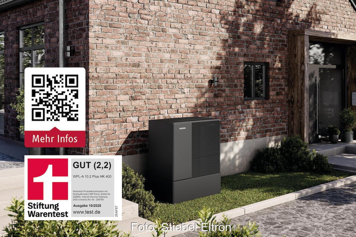 Eine schwarze Wärmepumpe steht vor einer geklinkerten Hausfassade.