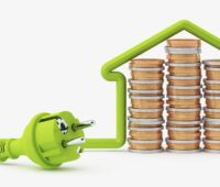 Ein Haus mit grünem Stecker und Türmen aus Münzen als Symbolbild für Stromkosten und Klimaschutz