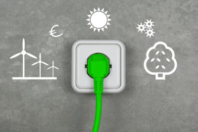 Graue Wand mit Symbolen für Windenergie, Sonne, Bioenergie und eine Steckdose mit einem grünen Stecker - Symbolbild für Ökostrom-Einspeisung