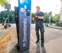 Ein Mitarbeiter der Stadtwerke Bonn checkt eine Ladesäule an einer Straße.