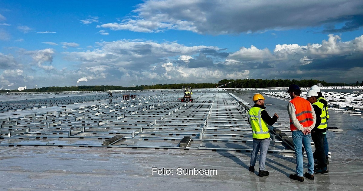 Im Bild Monteure auf einem Flachdach, die das Supra-Photovoltaik-Montagesystem von Sunbeam aufbauen.