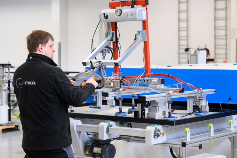 Sunmaxx-Mitarbeiter in Fabrikhalle an einem Arbeitstisch mit PVT-Modul.