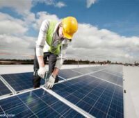 Montage von Solarmodulen durch Handwerker auf dem Flachdach