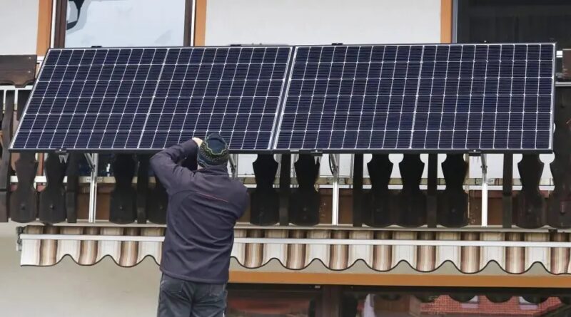 Im Bild ein Mann, der ein Balkonkraftwerk installiert. Die Balkonsolar-Petition an den Bundestag setzt sich für Erleichterungen ein.