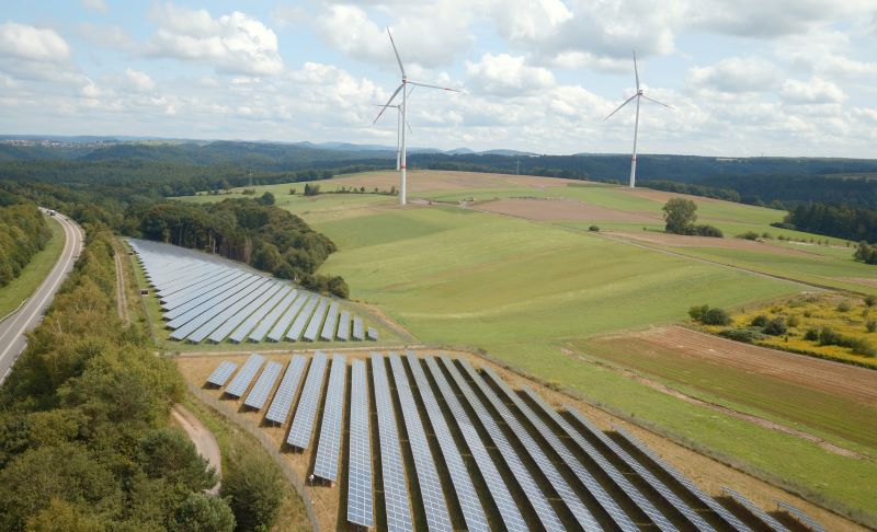 Eine PV-Park und Windenergieanlagen in flacher Landschaft.