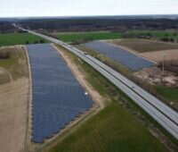 Luftbild eines PV-Parks zu beiden Seiten einer Autobahn.