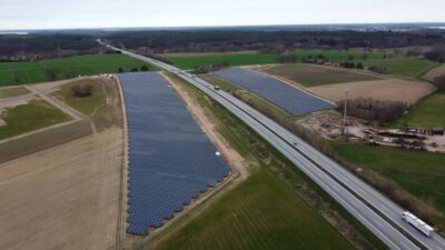 Luftbild eines PV-Parks zu beiden Seiten einer Autobahn.