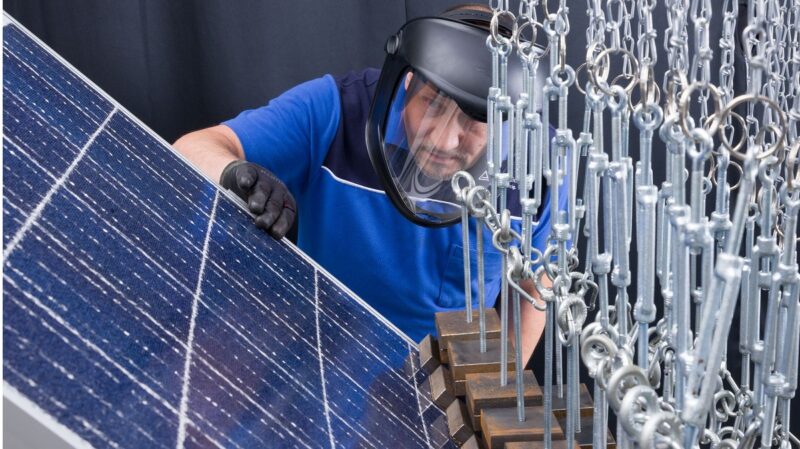 Zu sehen ist ein Teststand beim TÜV Rheinland, auf dem ein Mitarbeiter ein Photovoltaik-Modul auf die Beständigkeit gegenüber Schneelasten prüft.