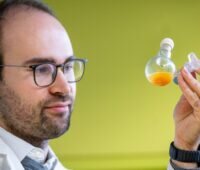 Im Bild ist Dr. Philip Stanley der das Nanomolekül für die künstliche Photosynthese in einem Kolben in der Hand hält.