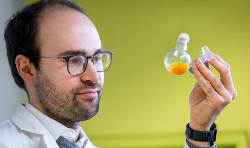 Im Bild ist Dr. Philip Stanley der das Nanomolekül für die künstliche Photosynthese in einem Kolben in der Hand hält.