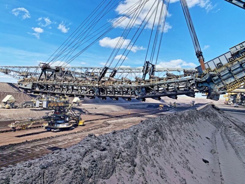 Eine riesige Maschine fährt über einen Kohleflöz im Tagebau.