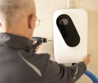 Zu sehen ist ein Monteur der die Ladebox für Elektroautos des Pakets Charging by EnOSTM installiert.