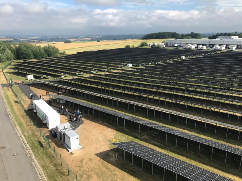 Vogelperspektive auf Photovoltaik-Großanlage und einen Container, in dem sich ein Batterie-Speicher befindet.