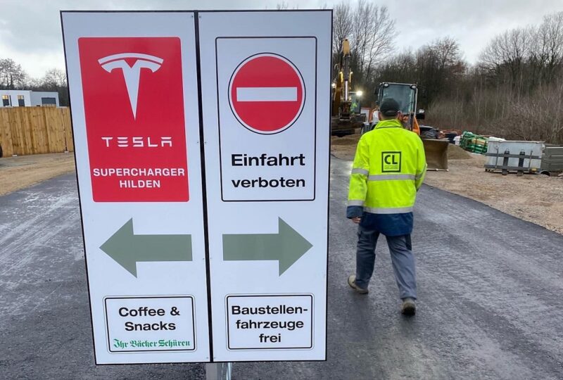 Ladepark Hilden: Zu sehen ist ein Schild, das zu den provisorisch aufgestellten Tesla-Superchargern führt.