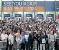 Menschenmasse vor Drehkreuz, oben ein Plakat mit Datum der Messe 2024