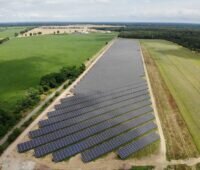 Luftaufnahme eines Freiflächensolarparks in landwirtschaftlich geprägter Umgebung.