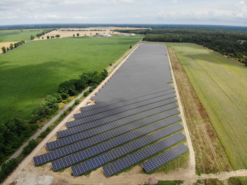 Luftaufnahme eines Freiflächensolarparks in landwirtschaftlich geprägter Umgebung.