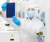 Im Bild ein Mensch im Labor mit einer Solarzelle, Trina Solar hat eine Rekordleistung für ein Photovoltaik-Modul erzielt.