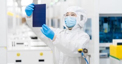 Im Bild ein Mensch im Labor mit einer Solarzelle, Trina Solar hat eine Rekordleistung für ein Photovoltaik-Modul erzielt.