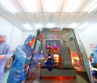 Mehrere Personen in Schutzanzügen bei der Prüfung einer Solarzelle im Labor.