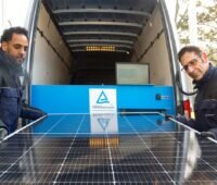2 Personen prüfen ein Solarmodul an einem Nutzfahrzeug.