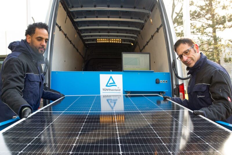2 Personen prüfen ein Solarmodul an einem Nutzfahrzeug.