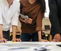 Menschen beugen sich über einen Tisch, Baden-Württemberg will die Wärmeplanung an die Vorgaben des Wärmeplanungsgesetzes anpassen.