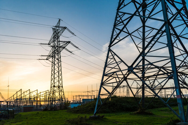 Stromnetze mit Hochspannungsmasten im Bereich eines Umspannwerks bei Sonnenuntergang