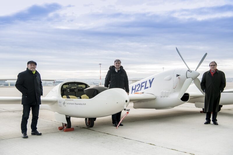 Zu sehen sind Baden-Württembergs Verkehrsminister Winfried Hermann, Hy4-Projektleiter Prof. Josef Kallo und Flughafengeschäftsführer Walter Schoefer bei der Präsentation vom Brennstoffzellen-Flugzeug.