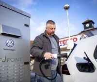 Das Foto zeigt einen Mann beim Laden seines Elektroautos.