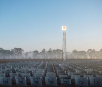 Gitterturm vor blauem Himmel, Spiegel sind darauf ausgerichtet, die Turmspitze scheint zu leuchten: ein CSP-Turmkraftwerk.