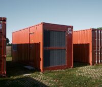 Rotfarbene Batteriecontainer auf grüner Wiese.