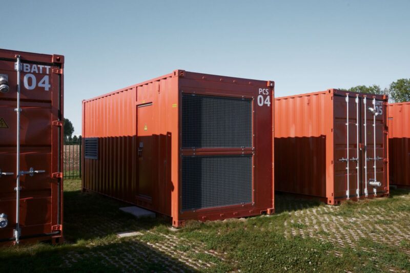 Rotfarbene Batteriecontainer auf grüner Wiese.