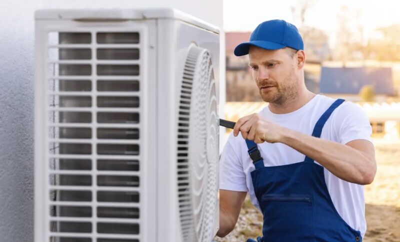 Ein Handwerker montiert eine Luftwärmepumpe.