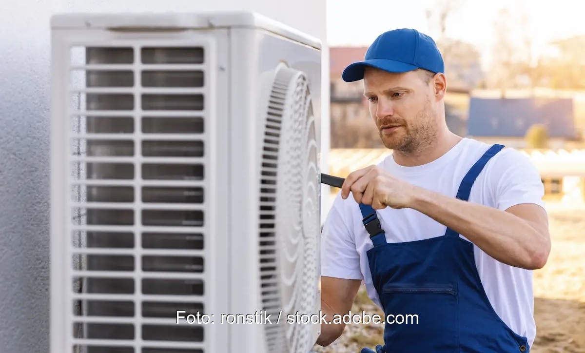 Ein Handwerker montiert eine Luftwärmepumpe.