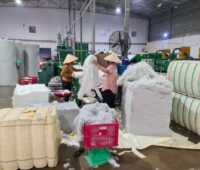 Zwei asiatische Frauen hantieren mit Polyester unf Baumwolle in einer Textilfabrik.