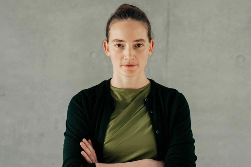 Portraitfoto Violetta Bock vor grauer Wand mit verschränkten Armen