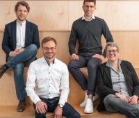 Vier Menschen auf Holzstufen - das Management-Team von Voltstorage will Redox-Flow-Batterien marktreif machen