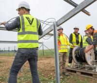 Arbeiter in Sicherheitswesten verlegen Kabel in einem PV-Park.
