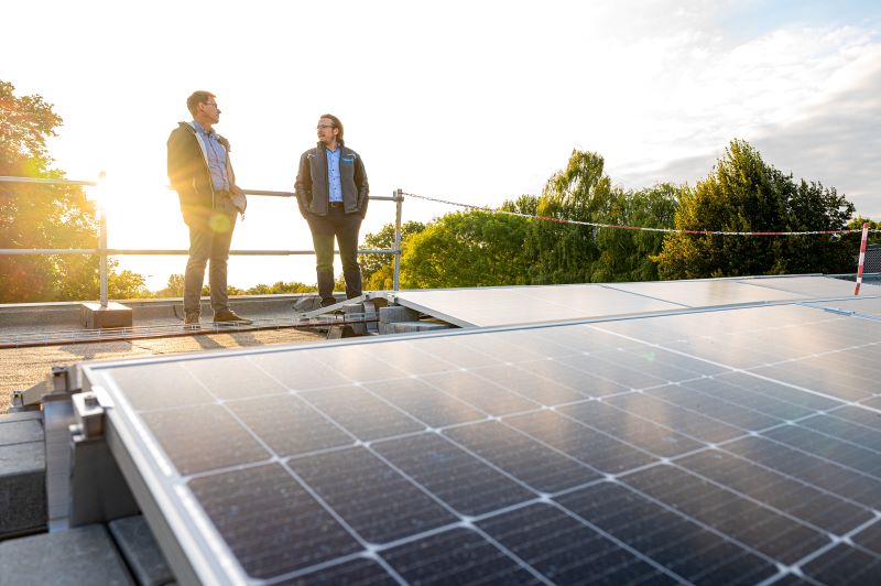 2 Männer im Gespräch auf einem Flachdach mit Photovoltaik.