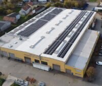 Luftbild eines Gewerbegebäudes mit PV-Anlage auf dem Dach.