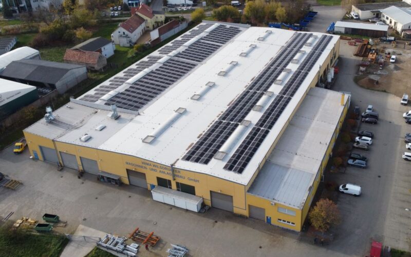 Luftbild eines Gewerbegebäudes mit PV-Anlage auf dem Dach.